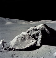 Apollo 17 astronaut Harrison Schmitt standing next to boulder at Taurus-Littrow during third EVA (extravehicular activity). NASA photo.